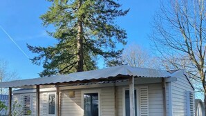 Ein kleines, eingeschossiges Mobilheim mit Veranda und überdachter Terrasse.