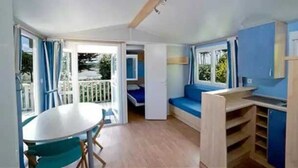 A compact room with a dining table, a blue sofa, and a small kitchen area.
