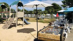 A playground with a slide, climbing structures, and a foosball table.