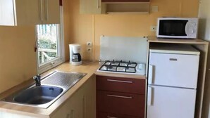 Une cuisine compacte équipée d’un évier, d’une cuisinière, d’un four à micro-ondes et d’un réfrigérateur.