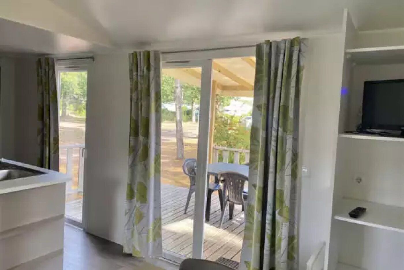 Une pièce comprenant un coin cuisine, une table à manger avec des chaises et un balcon donnant sur l’extérieur.