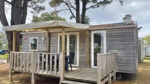 A small wooden cabin with a porch, a door, and a window. - ZEcamping 3 étoiles animé piscine chauffée locatif TV 27m2 4 pers (Guémené-Penfao)