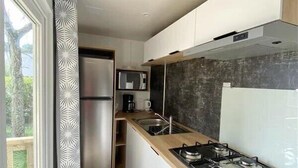 A modern kitchen with a built-in gas stove, stainless steel appliances, and a large window with a patterned curtain.