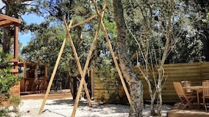 Eine Pergola aus Holz, ein Holztisch mit Stühlen und ein Zaun in einem Garten.