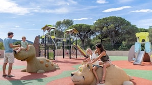 A playground with play structures, including a slide and climbing areas, surrounded by trees.