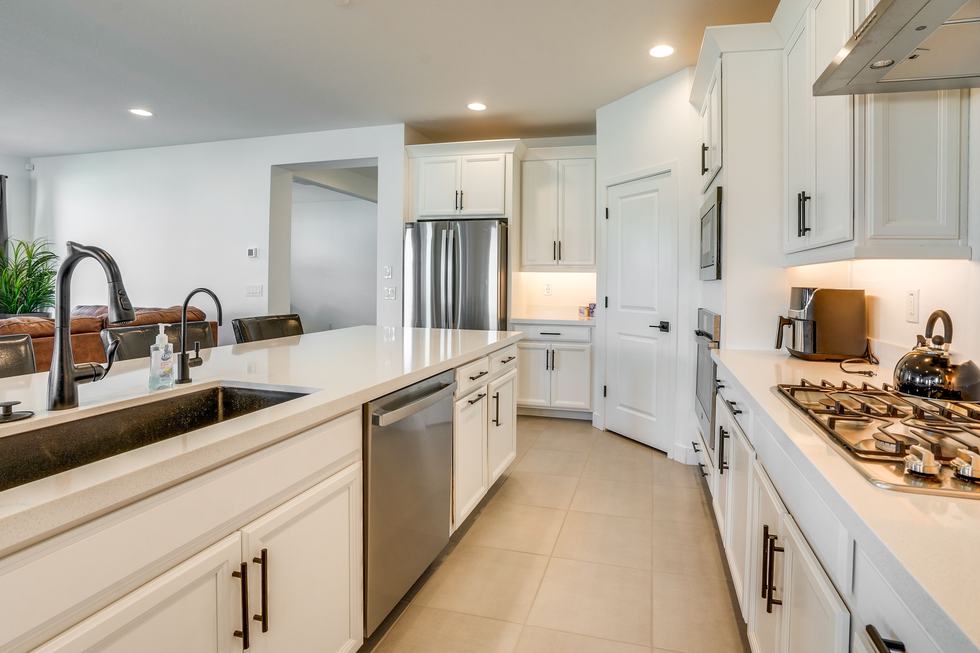 A modern kitchen with white cabinetry, stainless steel appliances, and a central island with a sink.