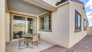 A patio with a table and chairs, a sliding glass door, and a textured exterior wall. - 5 Mi to Westgate! Newly Built Family Retreat (Glendale)