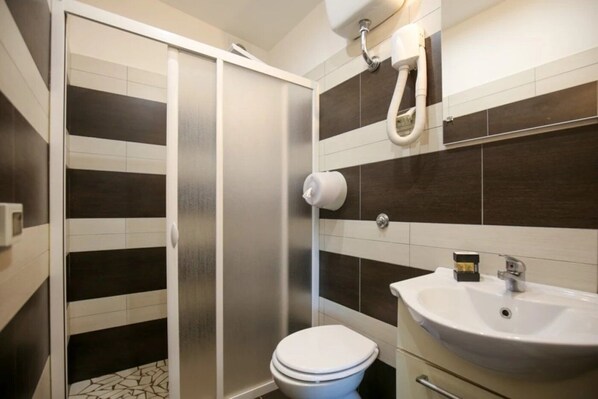 Un baño con inodoro, lavabo y ducha.