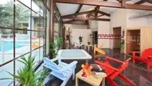 A modern indoor space with a pool view, a dining area with red chairs, and a large window. - ZEcamping 4* familial espace aquatique chiens acceptés locatif LV BBQ (Albi)