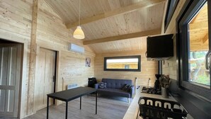 A wooden interior with a sofa, table, and kitchen area including a sink and stove.