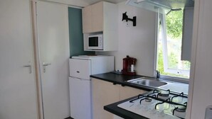 Eine kompakte Küche mit einer Mikrowelle, einem kleinen Kühlschrank, einem Spülbecken und einem Gasherd.