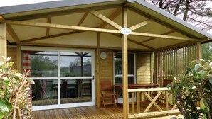 Une terrasse en bois dotée d’un espace salon couvert, d’une table et de chaises.