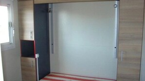Une petite pièce comprenant un lit, une armoire et un petit meuble.