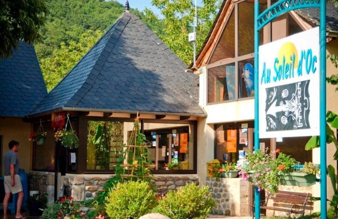 A building with a stone facade, a sloped roof, and a sign reading "Au Soleil d'Oc".