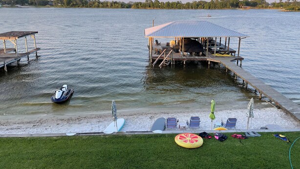 A lakeside dock with a covered seating area, lounge chairs, and a kayak. - Lake House (Lake Placid)