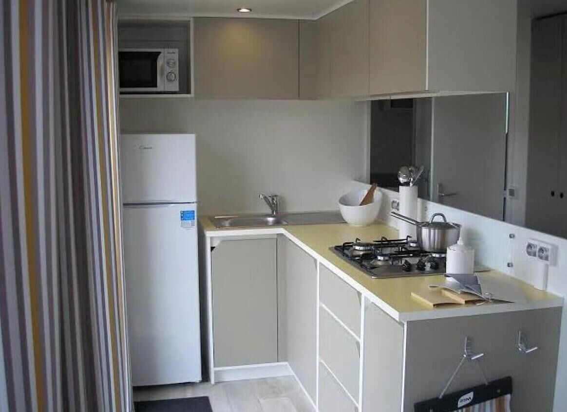 A compact kitchen with a microwave, refrigerator, gas stove, and a sink.
