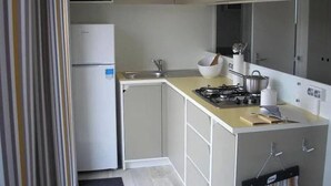 Eine kompakte Küche mit Mikrowelle, Kühlschrank, Gasherd und Spüle.