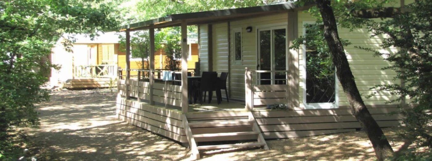 Une petite cabane avec une véranda, une table et des chaises.