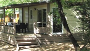 Uma cabana pequena com varanda, uma mesa e cadeiras.