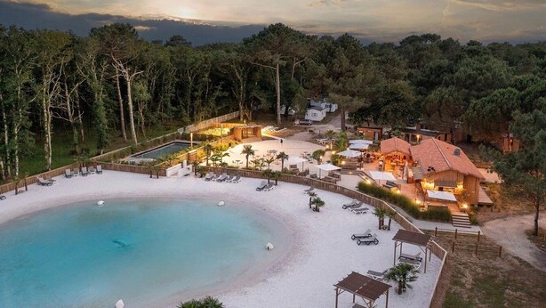 A resort with a large pool, beach area, and multiple buildings with outdoor seating.