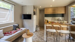 A modern kitchen with a wooden countertop, bar stools, and a built-in TV. - ZEcamping 4* parc aquatique pet friendly club enfant locatif TV LV (Les Mathes)