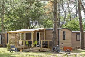 Une petite cabane avec une véranda, des sièges d’extérieur et un vélo.