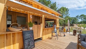 A wooden outdoor dining area with a menu board, wicker baskets, and potted plants. - ZEcamping 4* parc aquatique pet friendly club enfant locatif TV LV (Les Mathes)