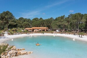 Un complexe hôtelier doté d’une grande piscine, d’une plage et de plusieurs bâtiments de style architectural méditerranéen.