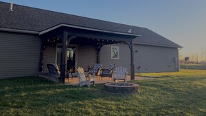 A house with a covered porch, outdoor seating, and a fire pit.