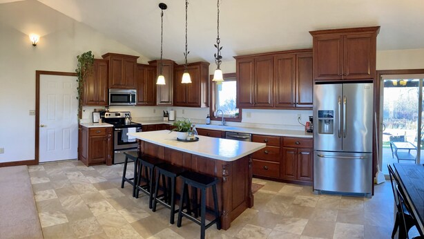 A modern kitchen with wooden cabinets, stainless steel appliances, and a central island with bar stools.