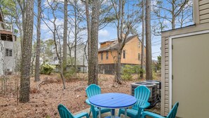 A backyard with a blue table and four chairs, surrounded by trees and a house. - Cozy Sea Pines Getaway! Features Community Pool and Short Walk to The Beach. (Bethany Beach)