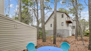 A two-story house with a fenced backyard, a blue table, and two blue chairs. - Cozy Sea Pines Getaway! Features Community Pool and Short Walk to The Beach. (Bethany Beach)