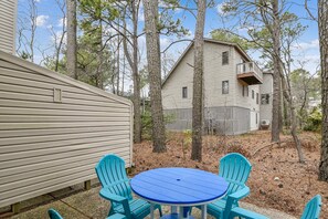 A two-story house with a fenced backyard, a blue table, and two blue chairs.