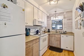 A modern kitchen with white cabinets, a stove, and a dishwasher.