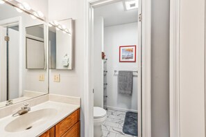 A bathroom with a sink, mirror, and toilet.