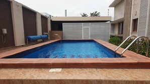 A swimming pool with a tiled deck and steps leading into the water. - MacDonald Apartments A5  (Lagos)