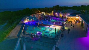 Ein Poolbereich mit mehreren Schwimmbecken, einer Bühne und einer Bar.
