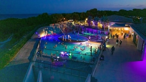 Un espace piscine comprenant plusieurs piscines, une scène et un bar.