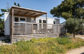 Une petite cabane à un seul étage, dotée d’une terrasse en bois et d’un porche couvert.