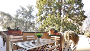 Eine Terrassengaststätte mit Holztischen und -bänken, umgeben von Kübelpflanzen und Bäumen.