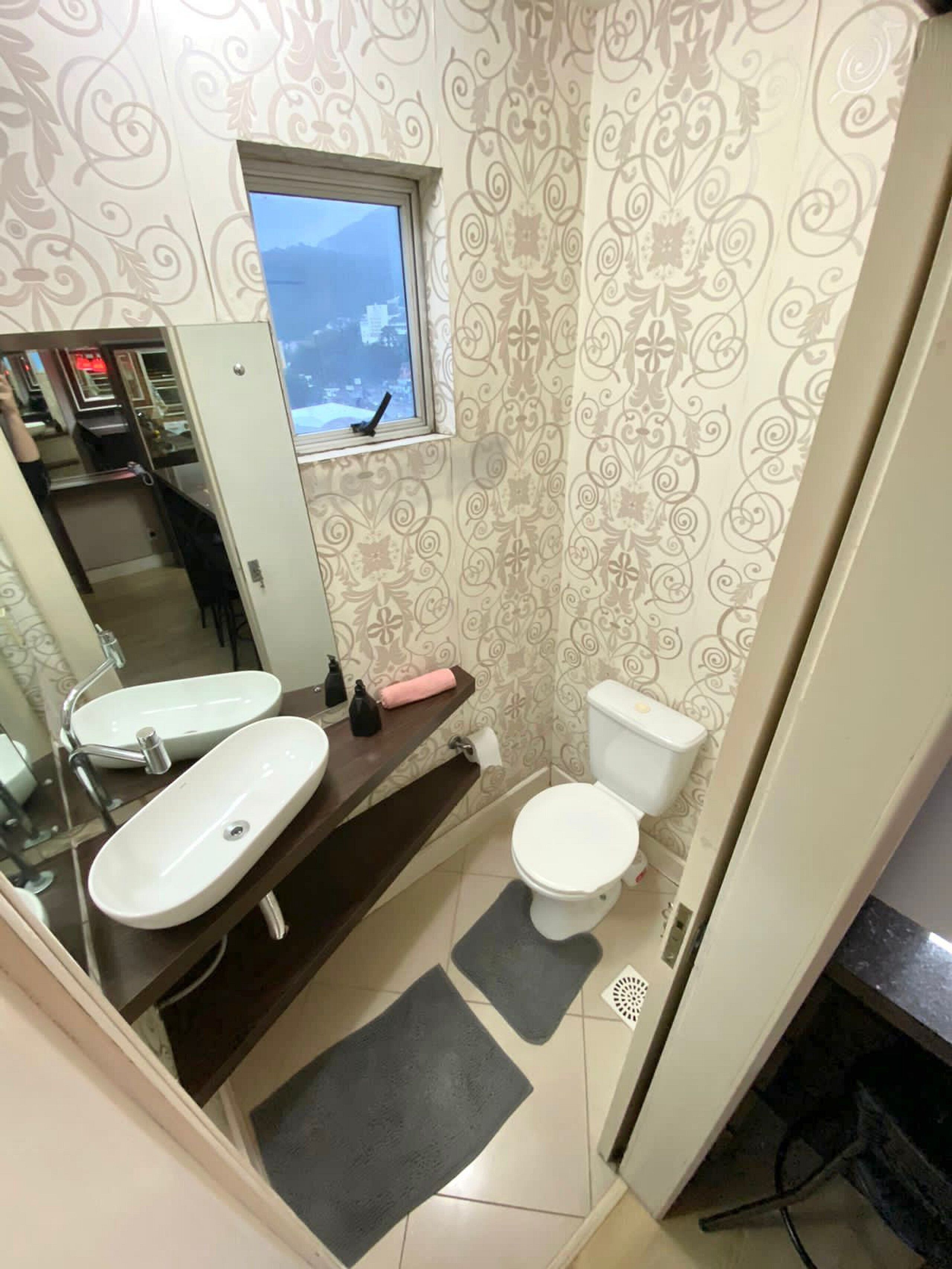 Un baño con dos lavamanos, un inodoro y una ventana con vistas al mar.
