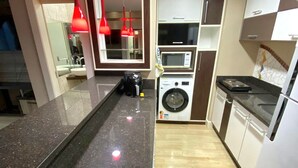 A modern kitchen with granite countertops, a built-in washing machine, and red pendant lights. - Saint Sebastian Flat 612 - Até 4 pessoas com hidro no centro (Jaragua do Sul)