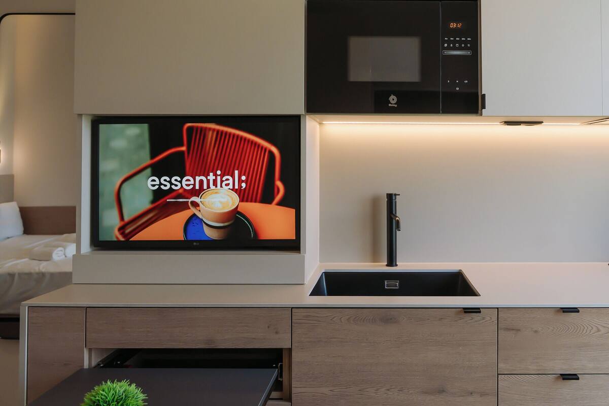 Een moderne keuken met een ingebouwde magnetron, een grote flatscreen-tv en een strakke zwarte kraan.