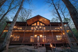 A multi-story log cabin with a prominent central roof, multiple balconies, and string lights. - Hickory Hollow Lodge (Sevierville)