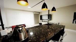 Una cocina moderna con encimera de granito, hervidor y luces colgantes.