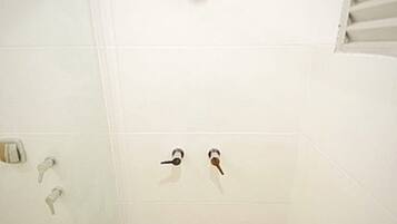A bathroom with a shower, a toilet, and a glass door.