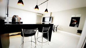 Una cocina moderna con encimera negra, electrodomésticos de acero inoxidable e iluminación colgante.