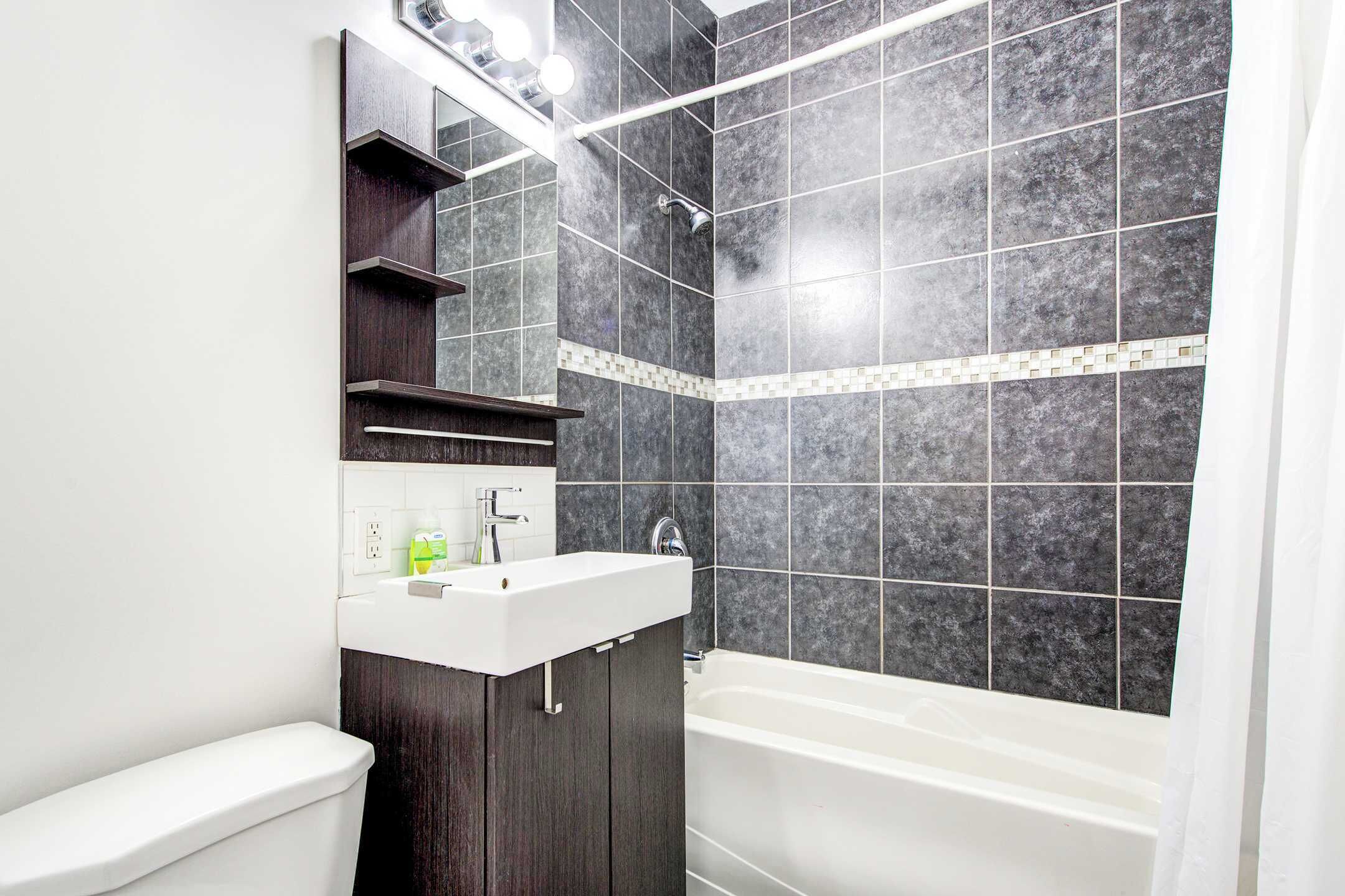 A modern bathroom with a white sink, dark wood vanity, and a bathtub.