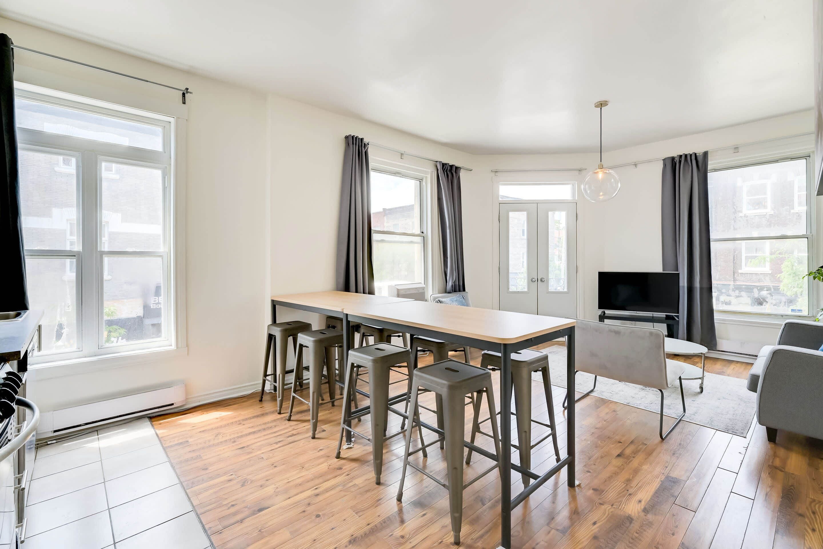 A modern kitchen with a wooden table, bar stools, and a built-in oven.