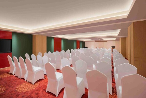 A conference room with rows of white chairs and a carpeted floor. - Fortune Park Tiruppur (Tirupur)